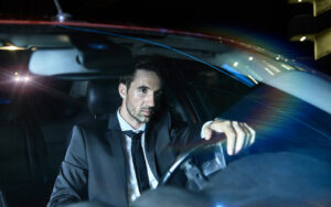 image of a serious looking man driving his car late at night