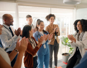 Doctor, coach and applause with team in meeting for collaboration, conference or health workshop at office. Medical professional. manager or leader clapping with employees for success at workplace